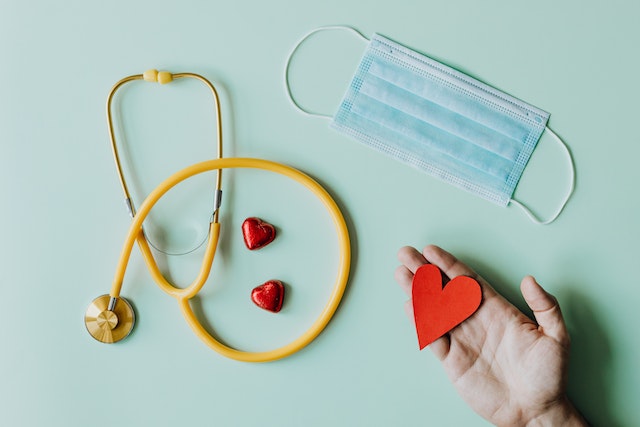An image of a hand with a mask and stethoscope and little hearts.
